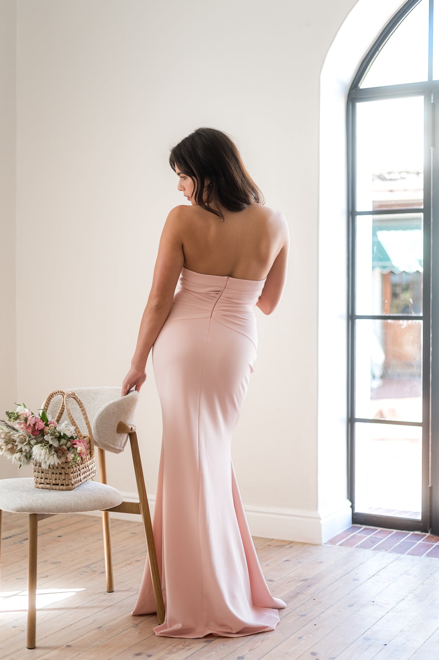 Woman in a strapless dusty pink bridesmaid dress from the back.