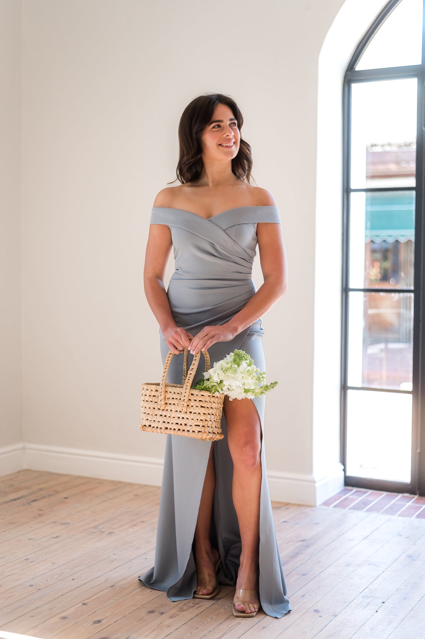 Woman in a  a  Sage, off-shoulder bridesmaid dress featuring a sweetheart neckline, rouging over the tummy and a cross-over slit. 